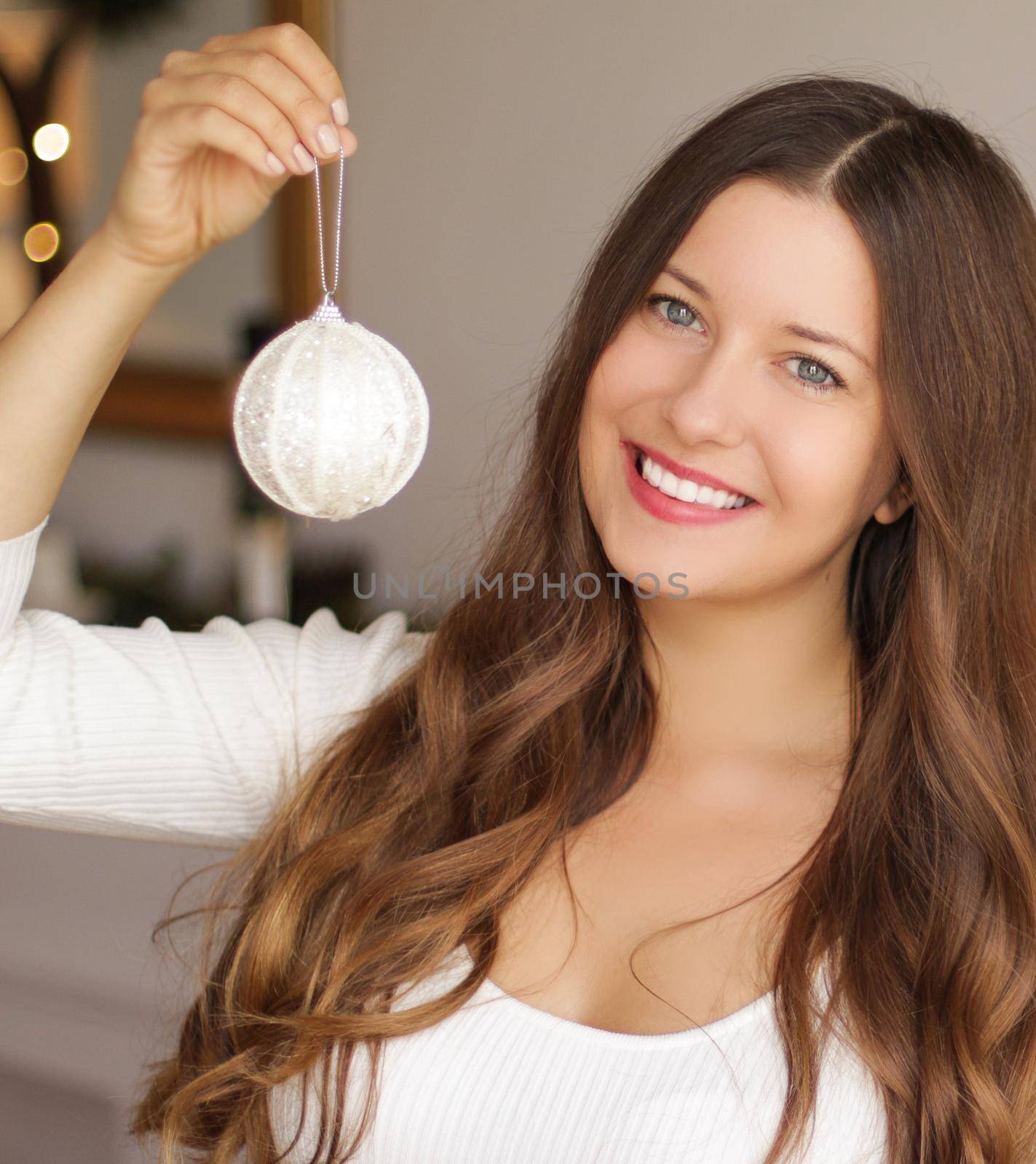 Decorating Christmas tree and winter holidays concept. Happy smiling woman holding festive ornament at home.