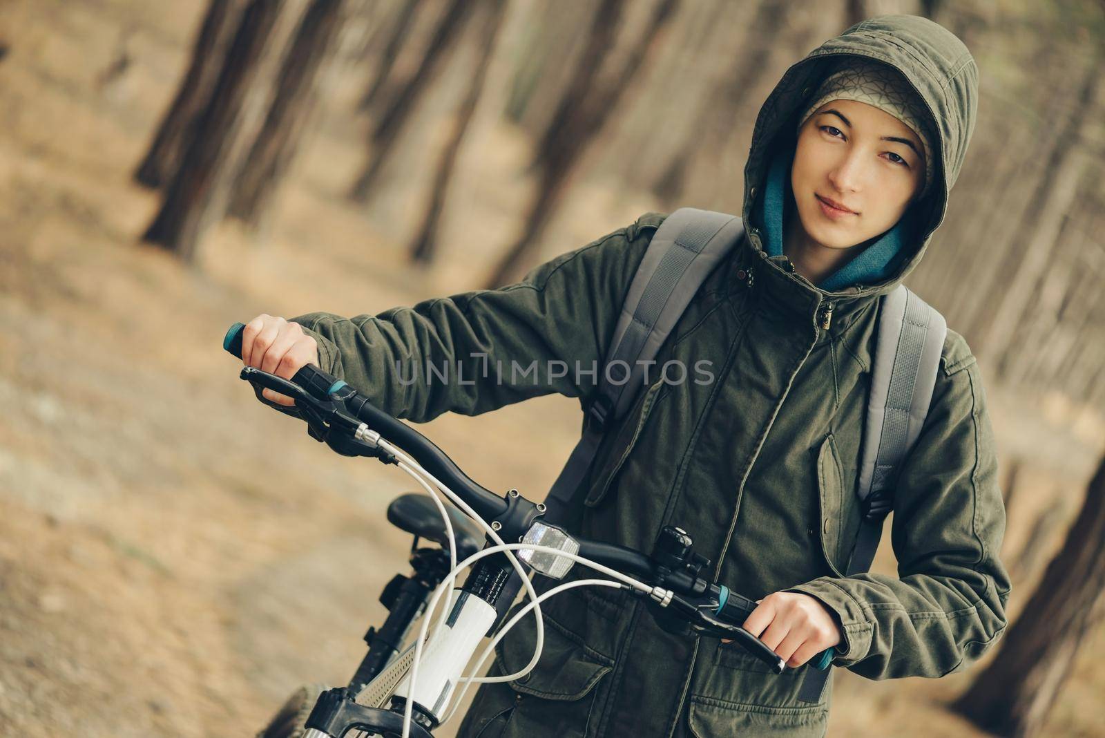 Hiker young woman walking with bicycle in a pine forest