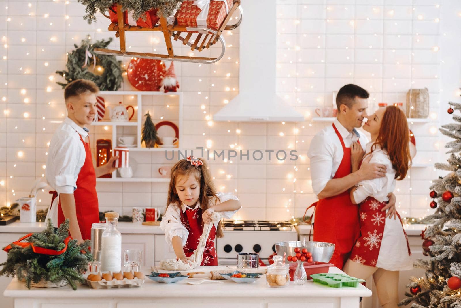 A little girl in the New Year's kitchen makes dough and her family helps her by Lobachad