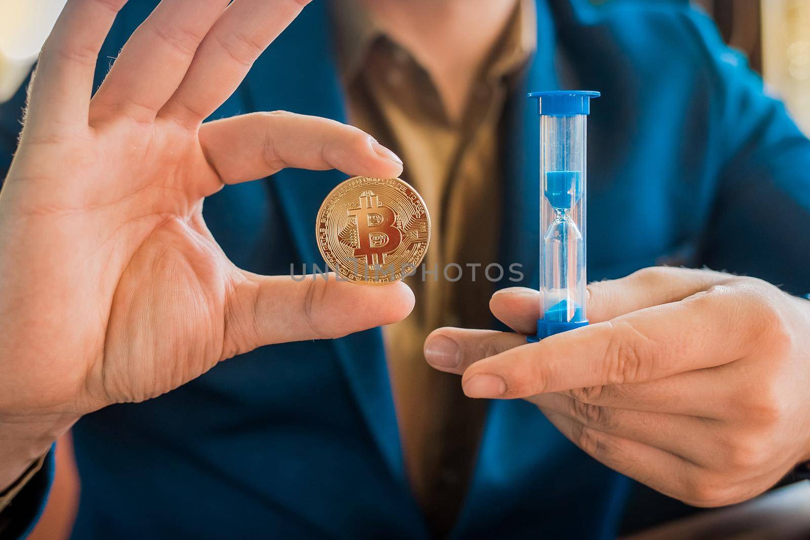 Businessman hands hold gold cryptocurrency bitcoin and hourglass. Cryptocurrency and bitcoin concept by AYDO8