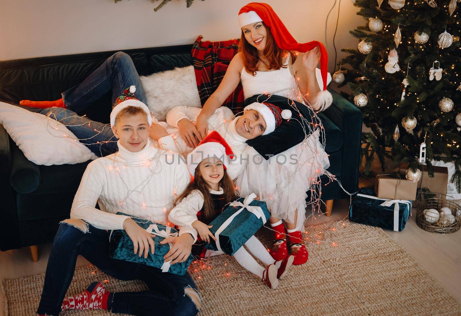 Close-up portrait of a happy family sitting on a sofa near a Christmas tree celebrating a holiday.