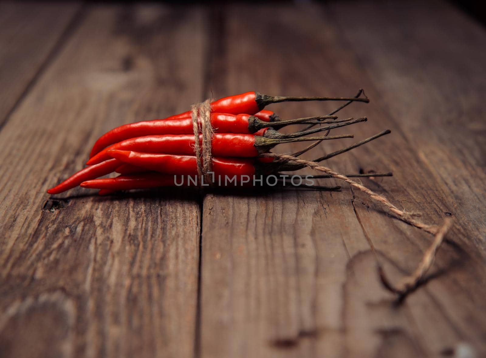 Red chili peppers in a bunch on a wooden table, focus on peppers