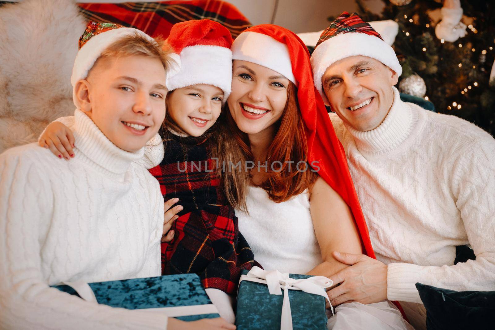 Close-up portrait of a happy family sitting on a sofa near a Christmas tree celebrating a holiday by Lobachad