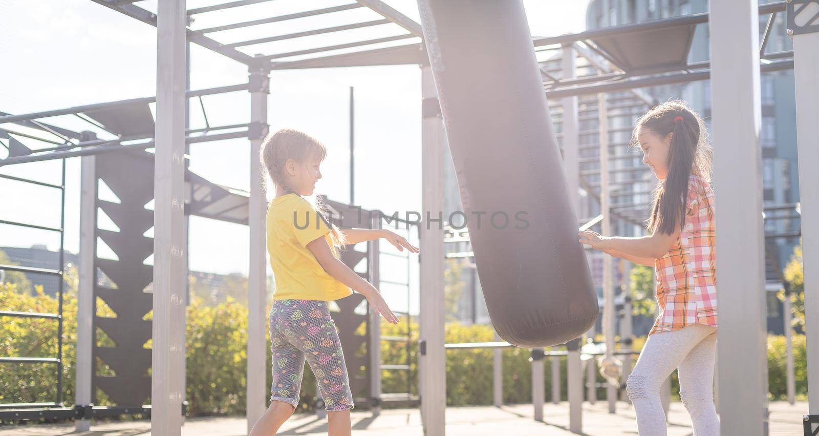 Two cute little girls having fun on a playground outdoors in summer. Sport activities for kids.