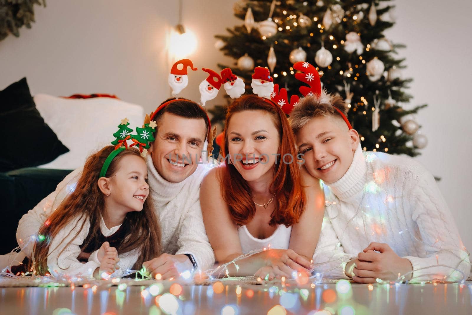 Close-up portrait of a happy family lying near a Christmas tree celebrating a holiday.