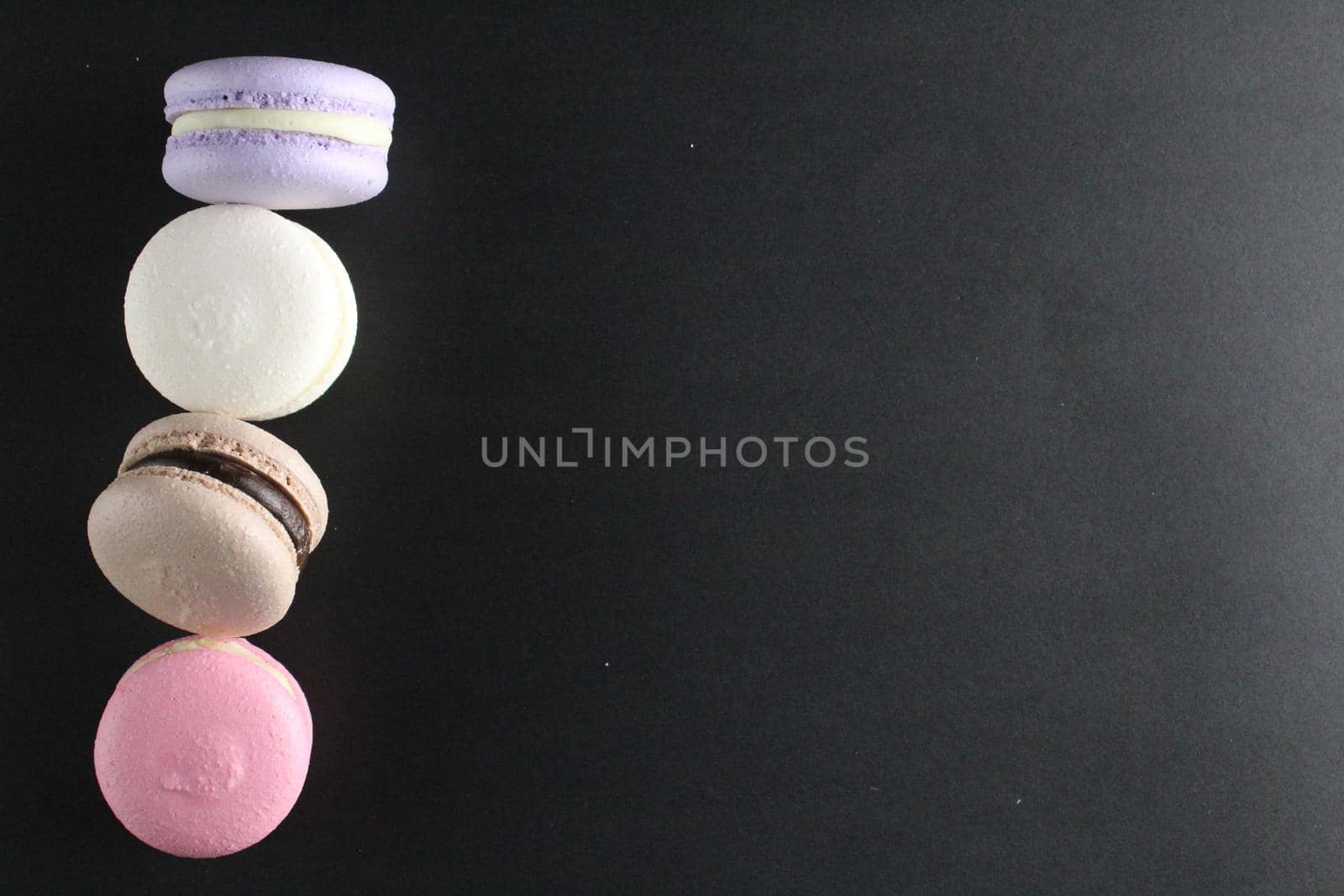 Four macaroons view from above on a black background with a place for text and with copyspace cooking.