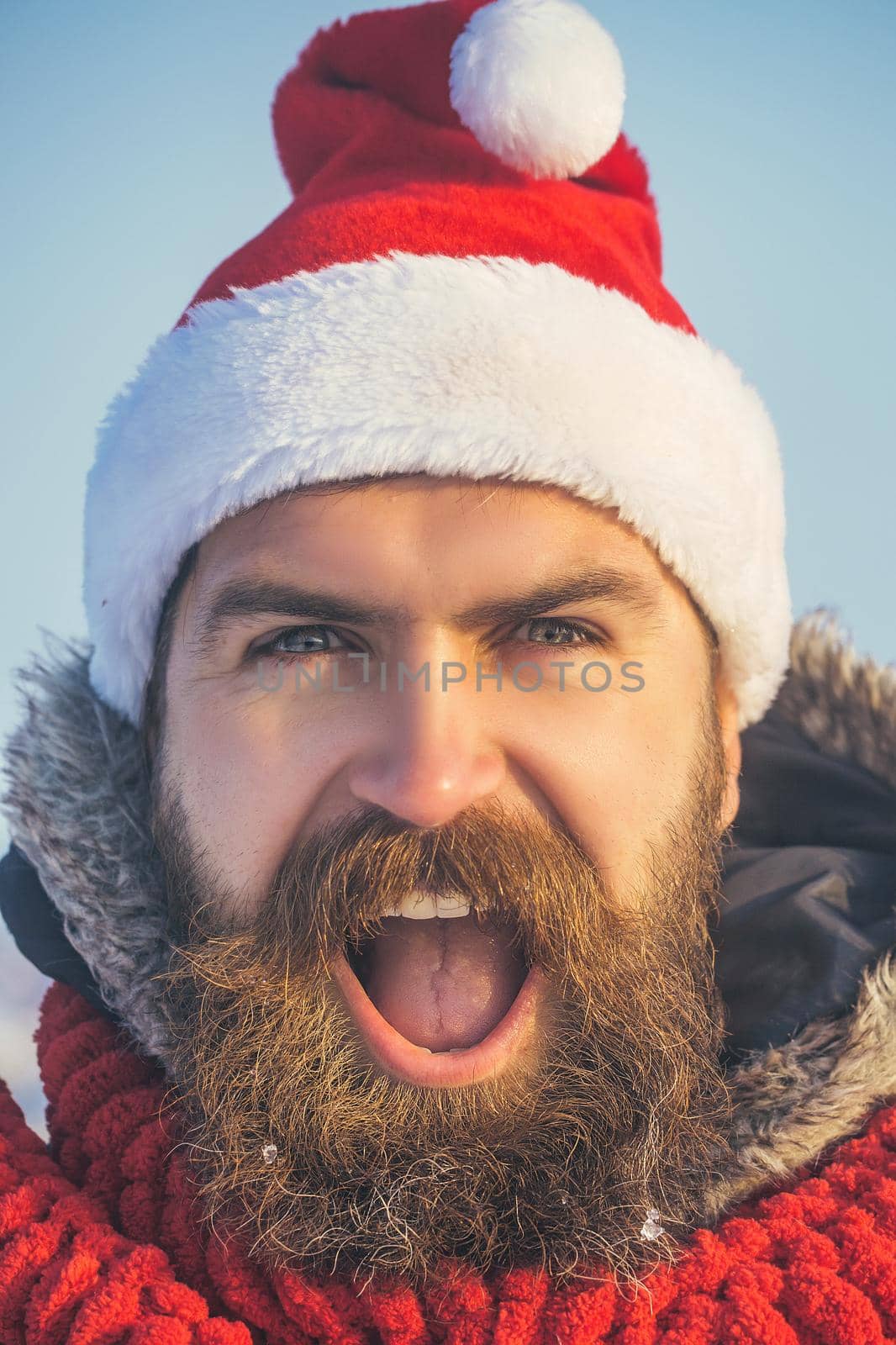 Santa claus hipster face in red hat and scarf. Christmas man with long beard and mustache on face.
