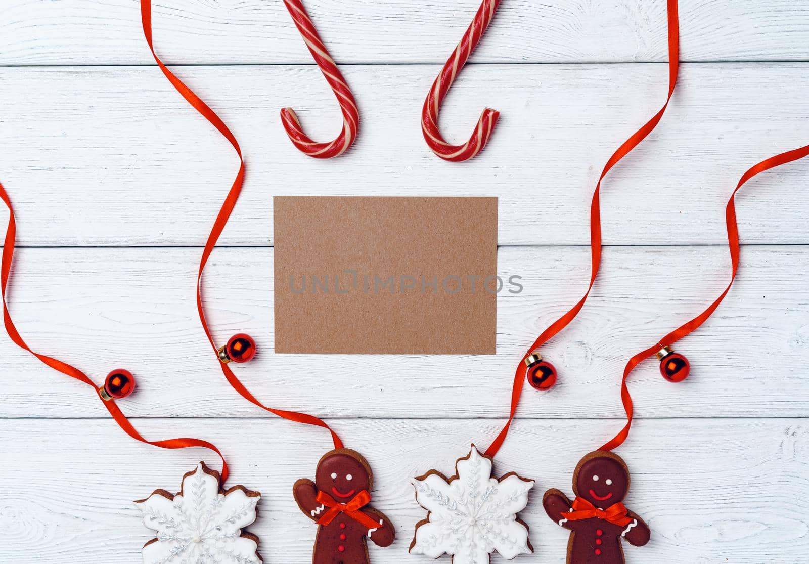 Winter festive background with gingerbread man and candy canes on white wooden board,l copy space