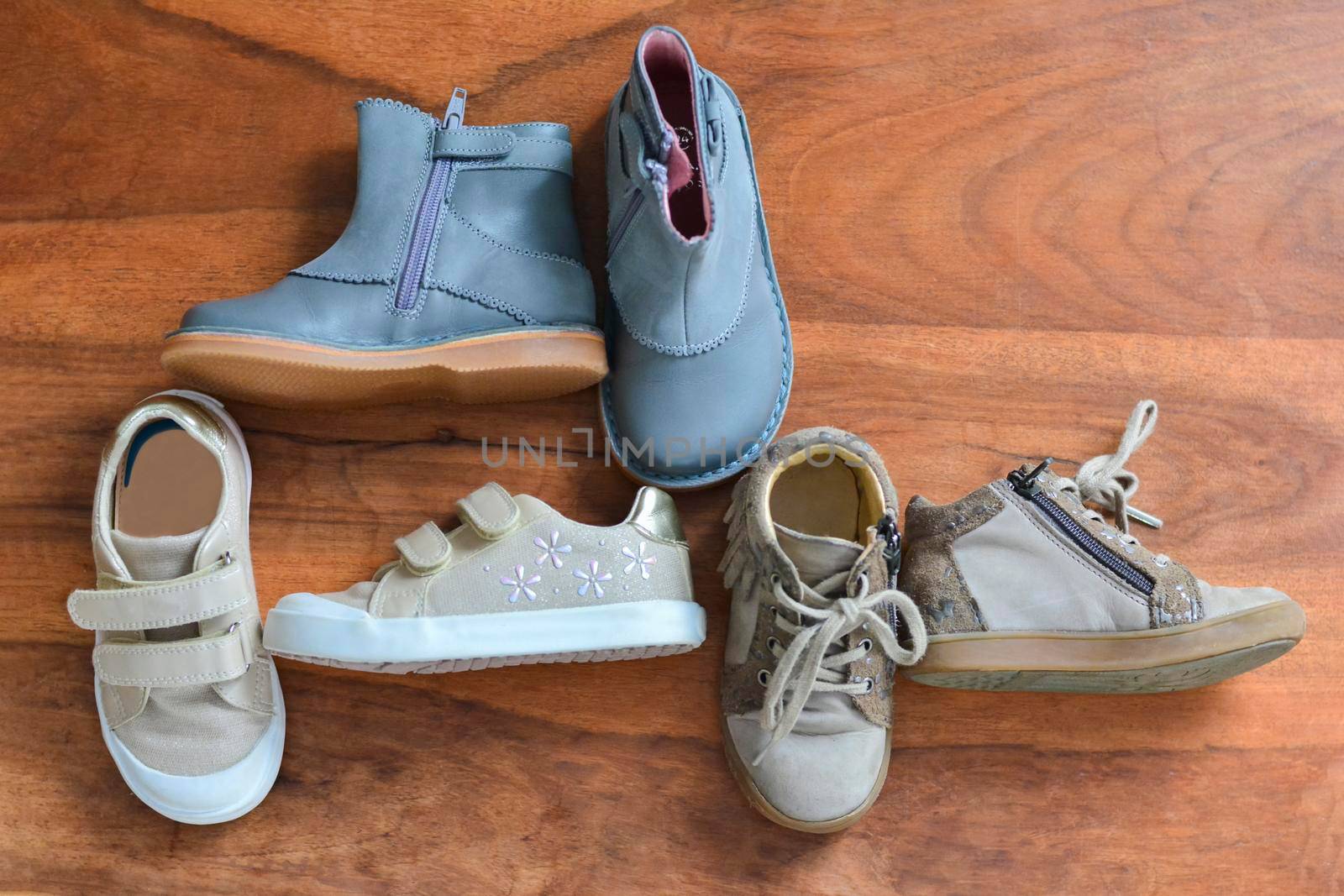 Different children's shoes on a wooden background