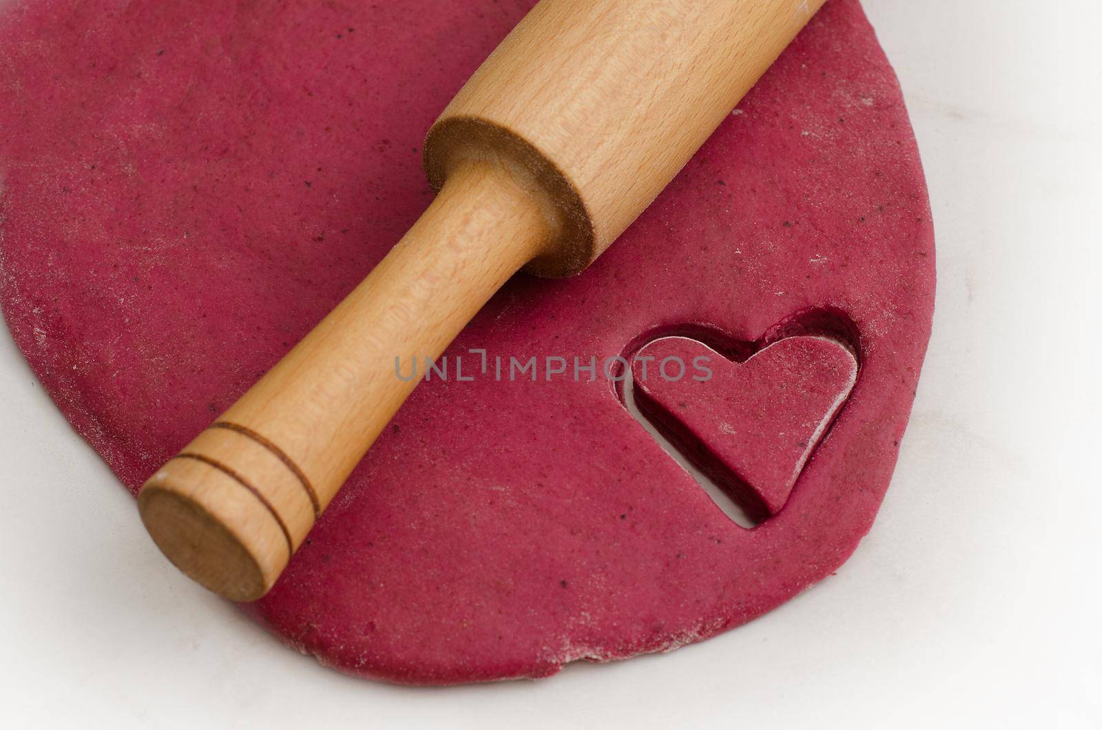 Sheet dough with red heart-shaped cut-out, preparing for Valentine's Day