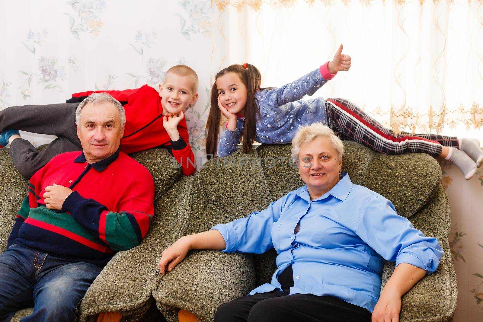 Grandparents and their young grandchildren relaxing at home by Andelov13