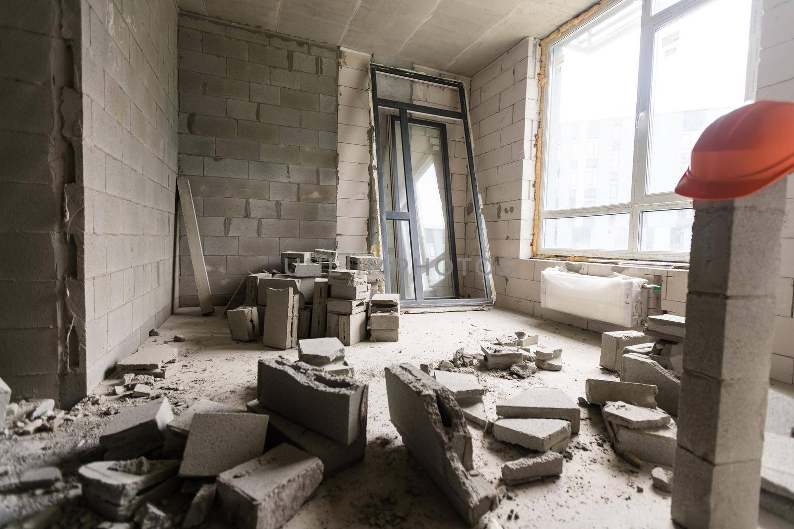 Break the wall for renovation and build the door for entrance of building. Wheelbarrow with broken bricks in site construction.