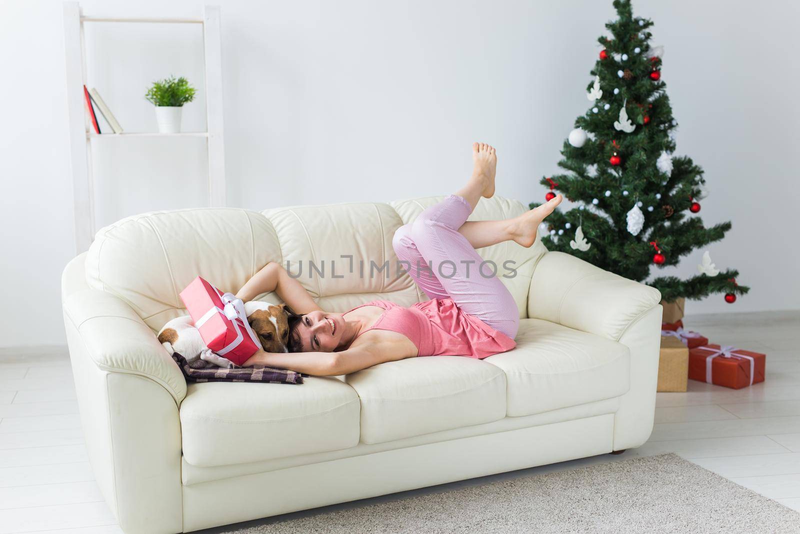 Happy young woman with lovely dog in living room with christmas tree. Holidays.