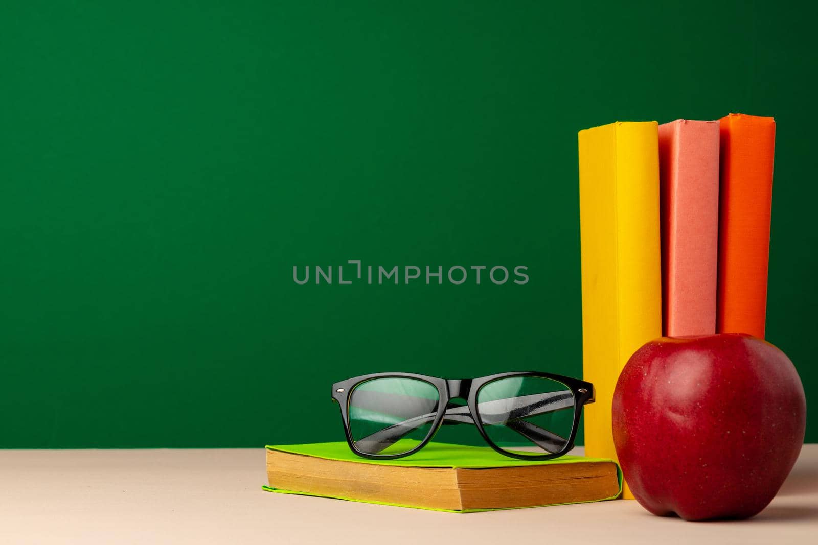 Pile of books and red apple on desk. Back to school concept