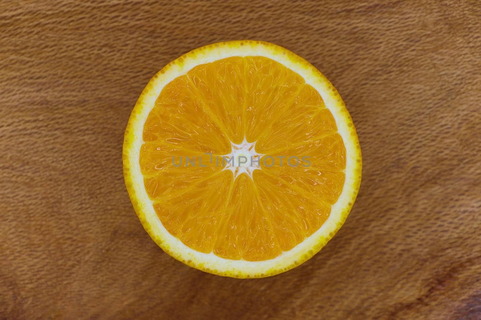 Single sliced valencia orange fruit (Citrus x sinensis) centered on wood surface