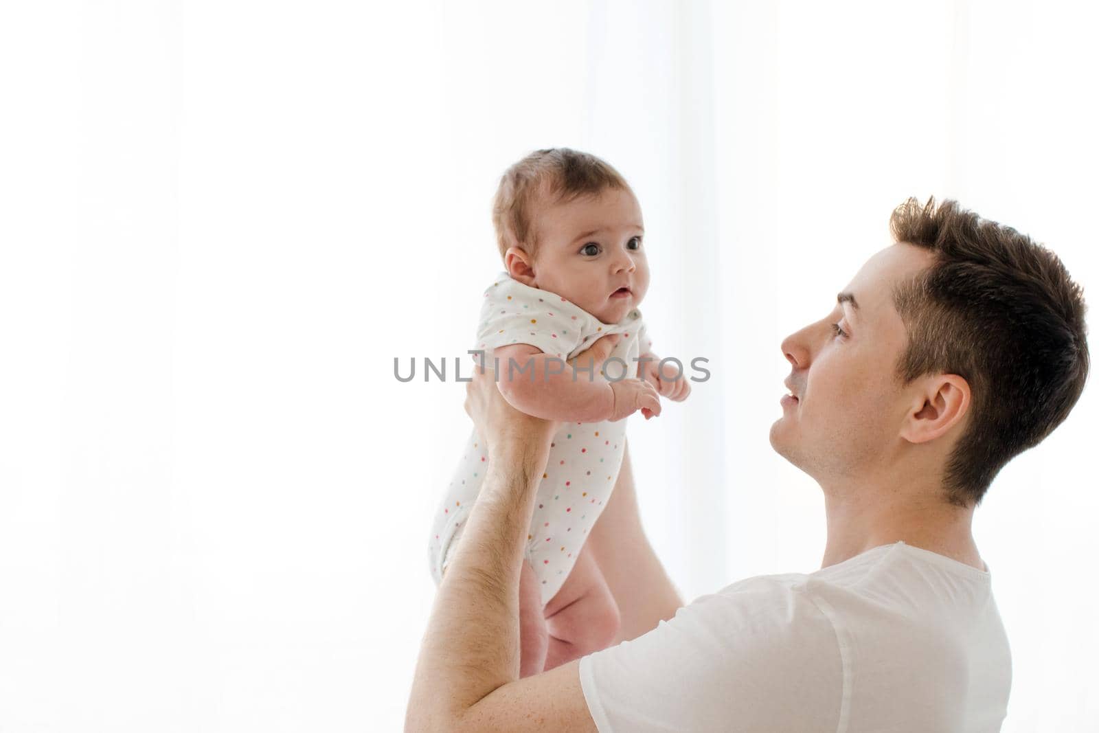 Side view of young man holding adorable newborn baby in hands isolated on white background