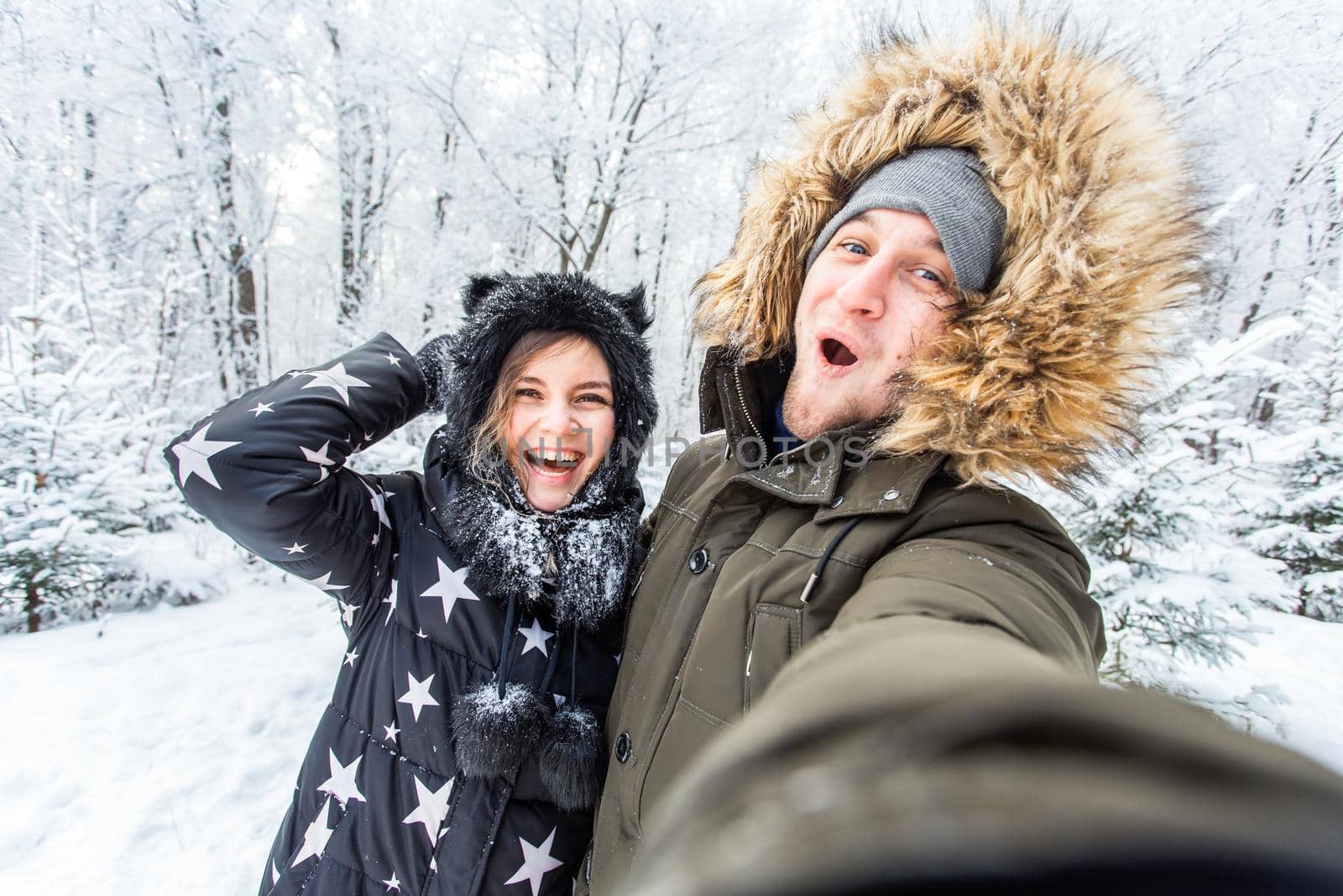 Season and relationship concept - Funny couple taking selfie in the winter time.