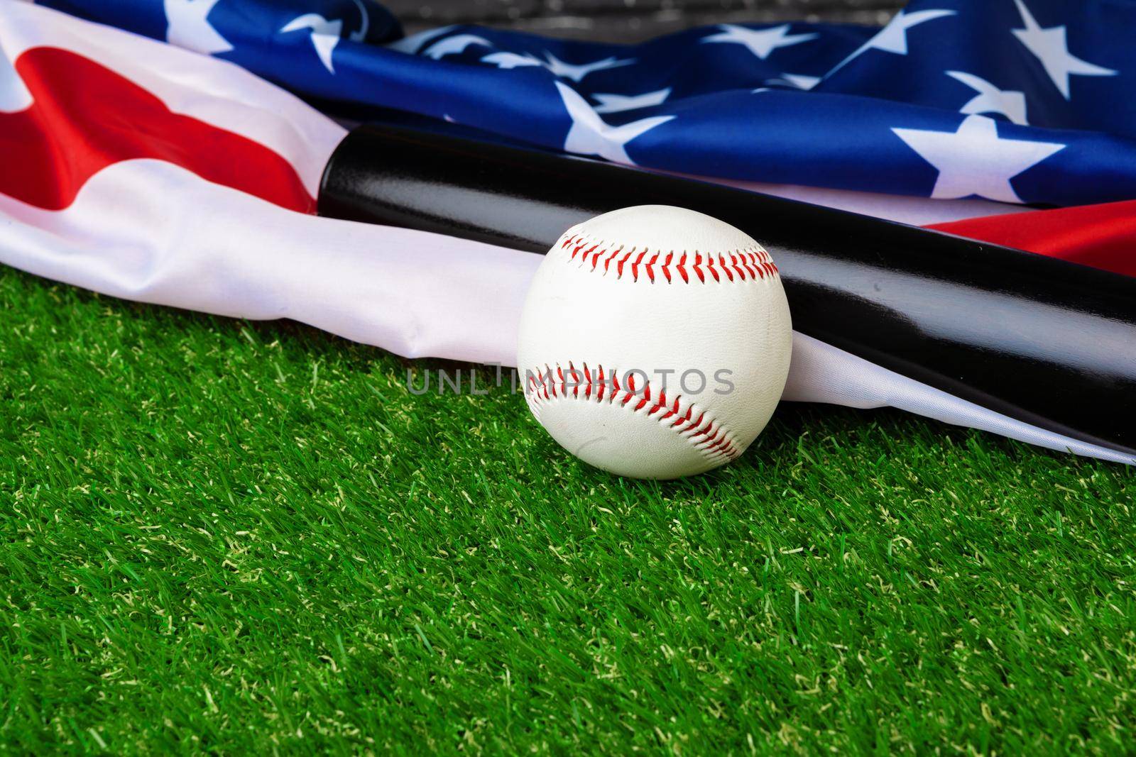 Baseball bat and ball with american flag on grass. Close up.