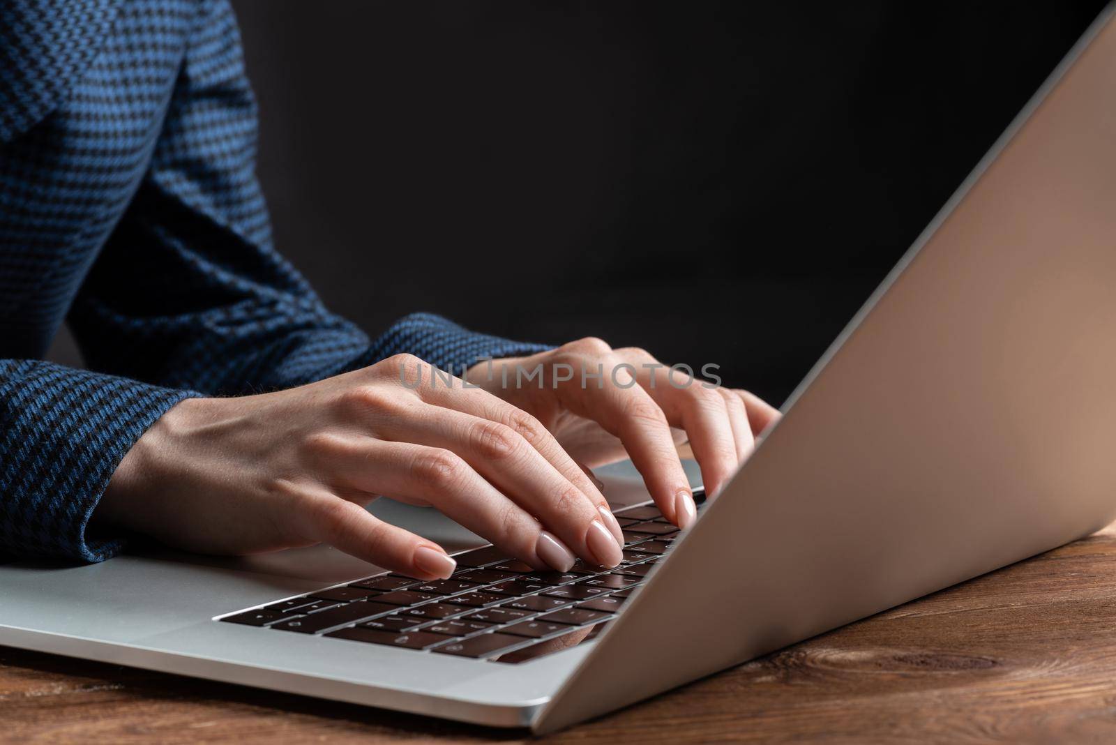 Close up woman hands lying on laptop keyboard. Business lady working with computer at wooden desk. Financial specialist working at workplace in office. Business accounting and project management.