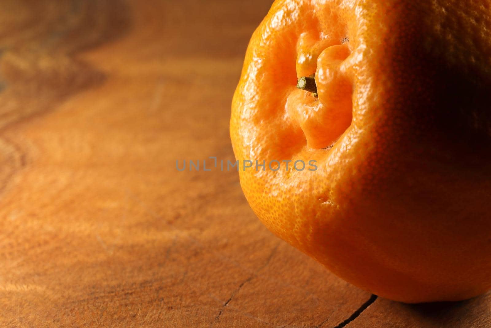 Fresh satsuma mandarin tangerine (Citrus unshiu) citrus fruit on natural wood abstract close-up