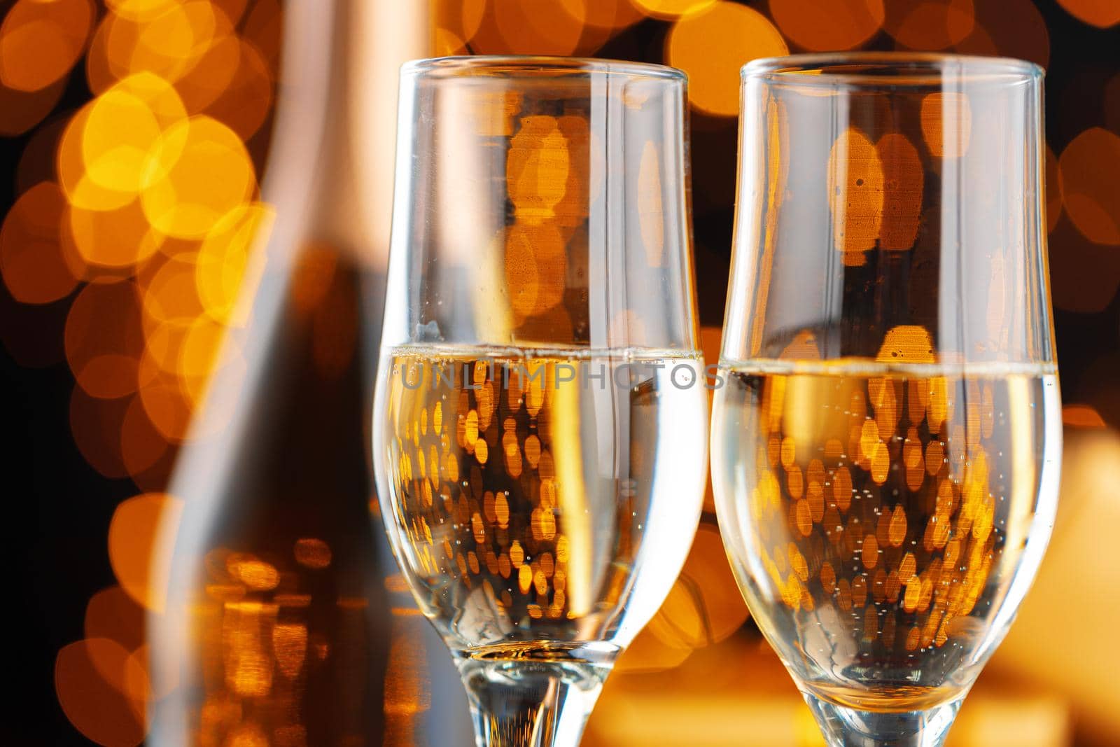 Champagne glass on blurred garland lights background close up
