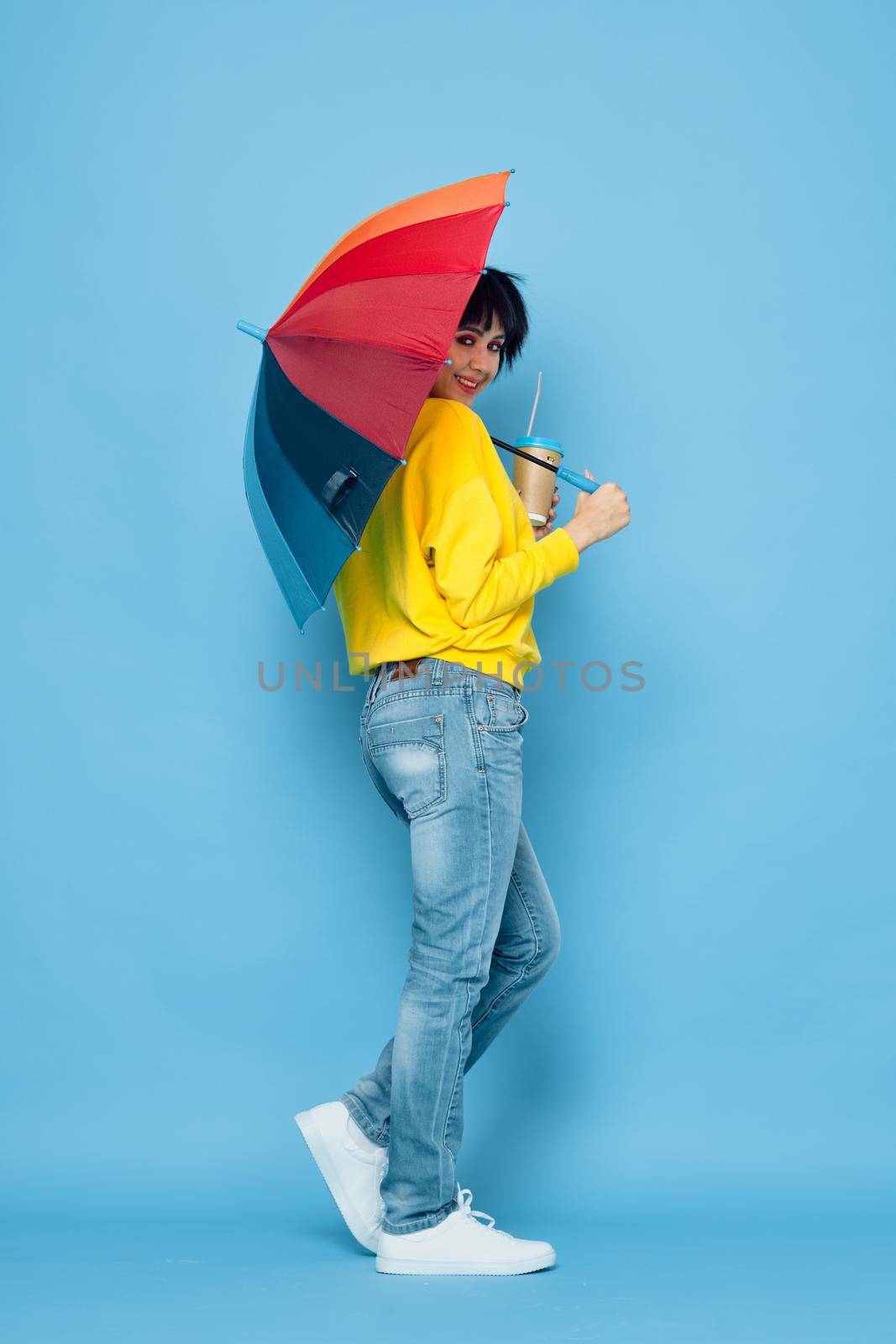 cheerful woman with rainbow colored umbrella posing street style. High quality photo