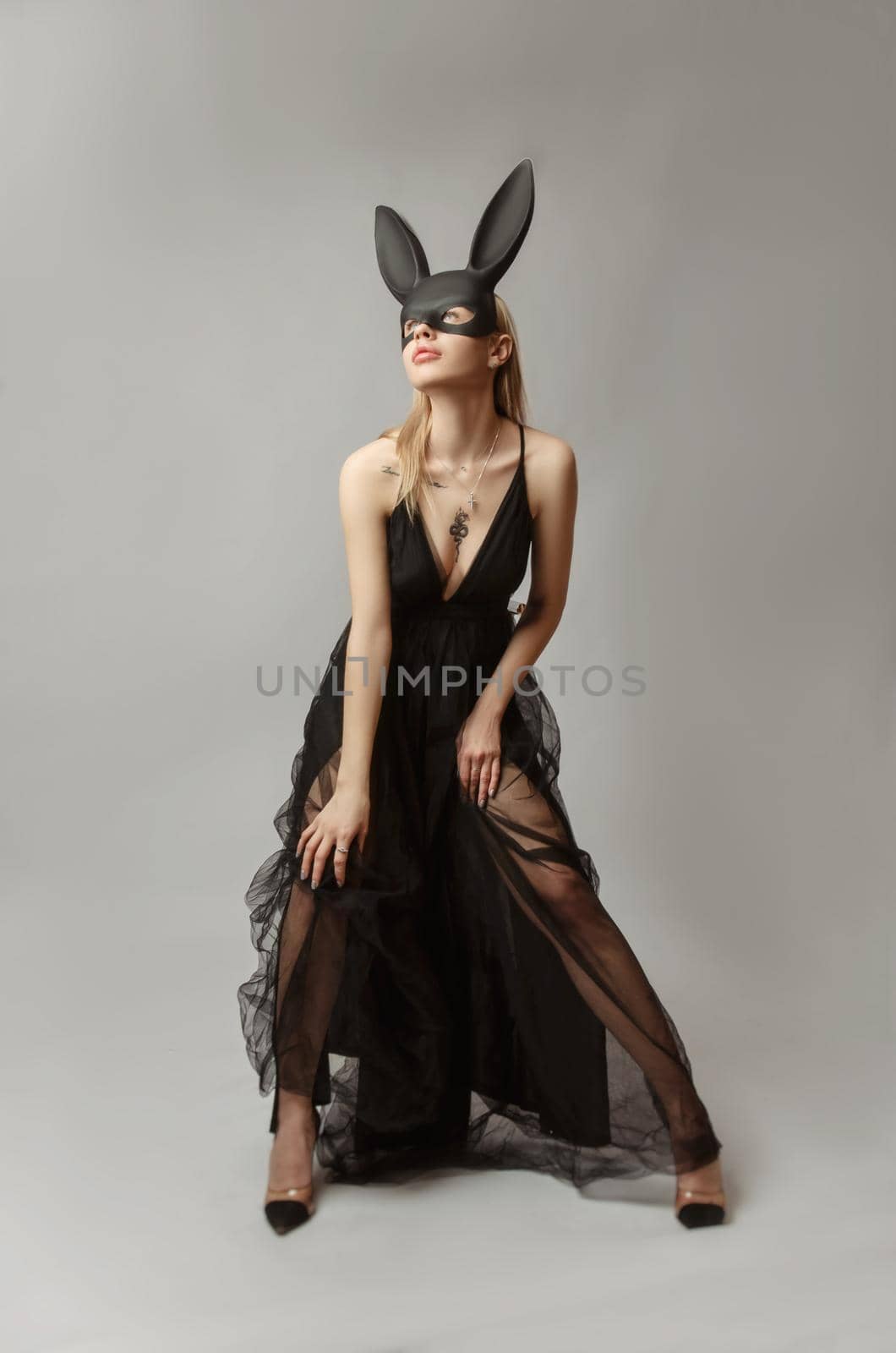 the Beautiful blonde in a rabbit mask in a sexy evening dress on a white background