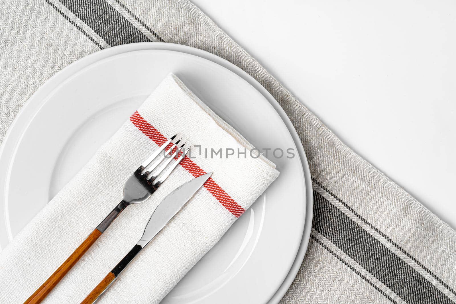 Fork, knife and plate on towel. Isolated on white background. Close up.