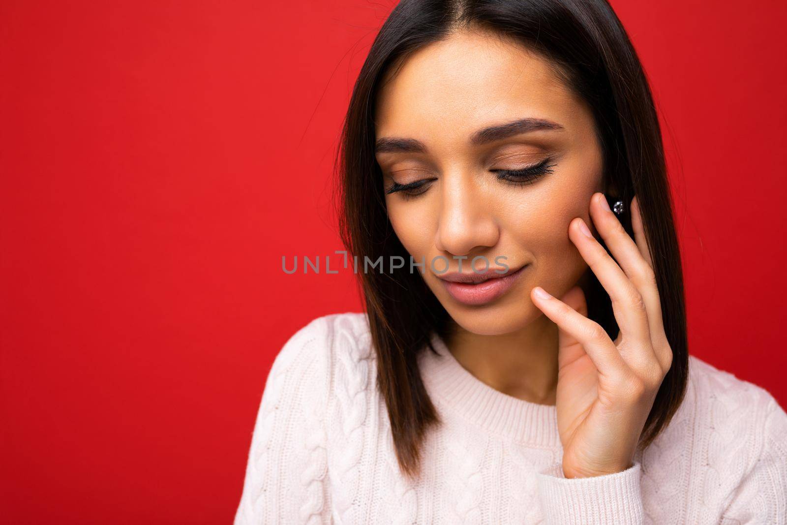 Closeup portrait of fascinating cute nice adorable tender young brunette woman in casual light knitted sweater isolated on red background with free space and enjoying.