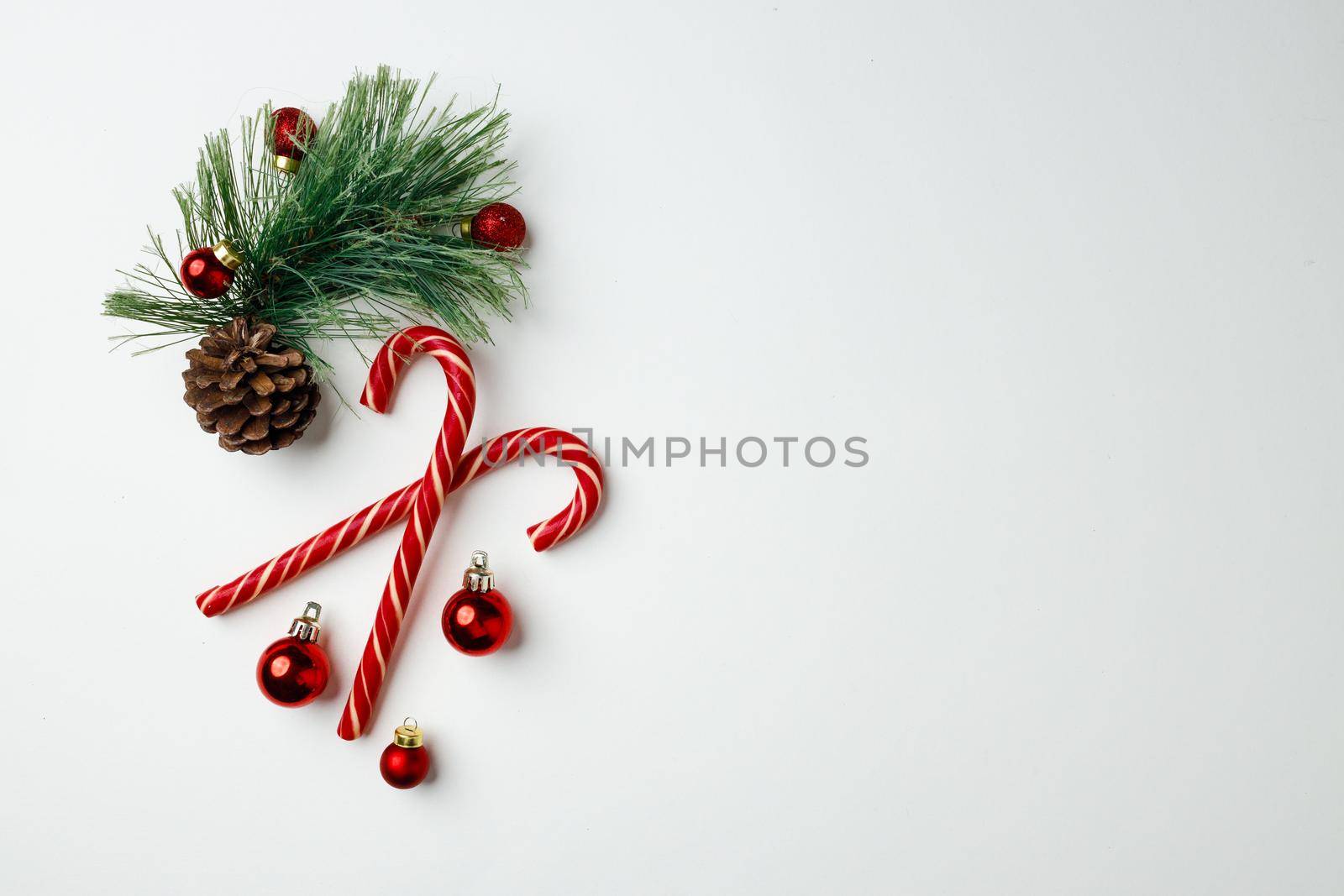 Candy canes and red Christmas baubles on white top view