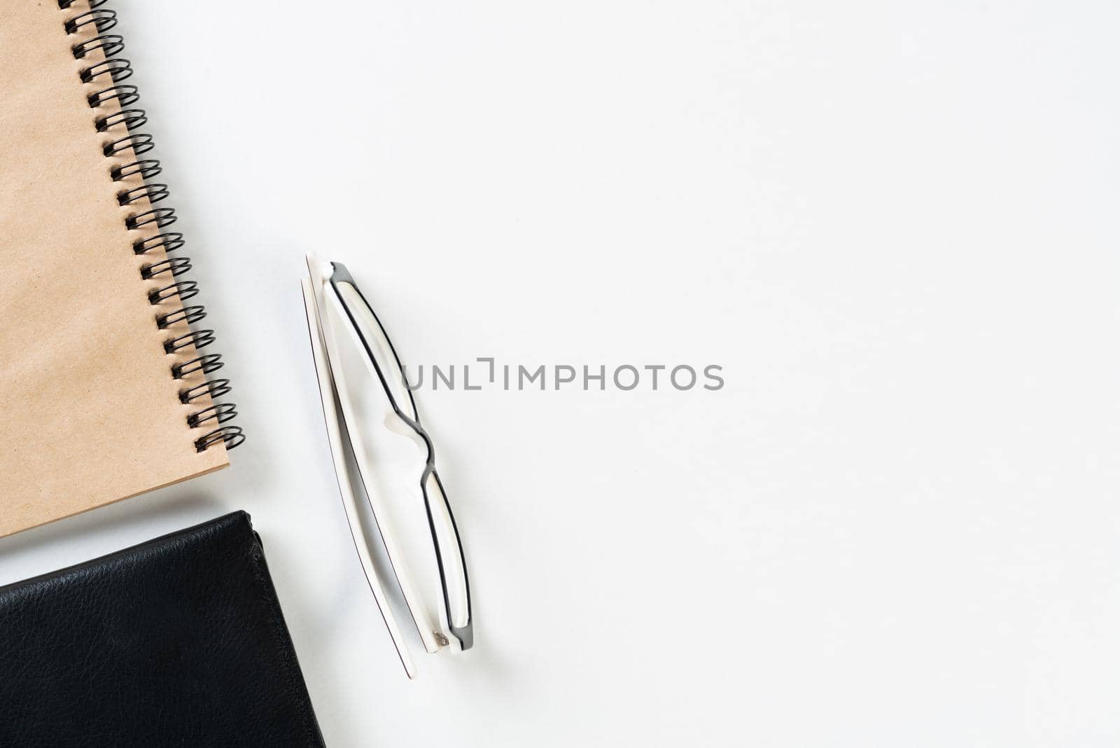 Still life of modern office workspace with supplies. Flat lay white desk with black leather wallet and spiral notepad. Accounting and banking service. Finance and investment concept with copy space