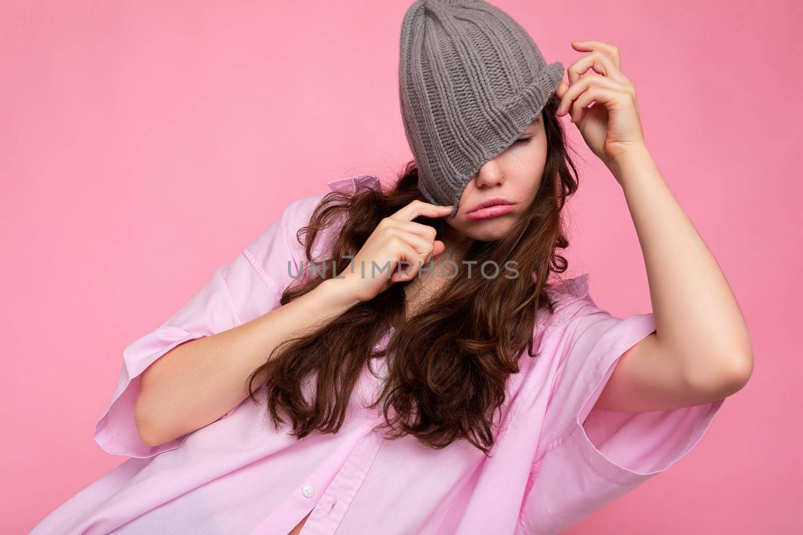 Attractive smiling happy young brunette woman standing isolated over colorful background wall wearing everyday stylish outfit showing facial emotions having fun.