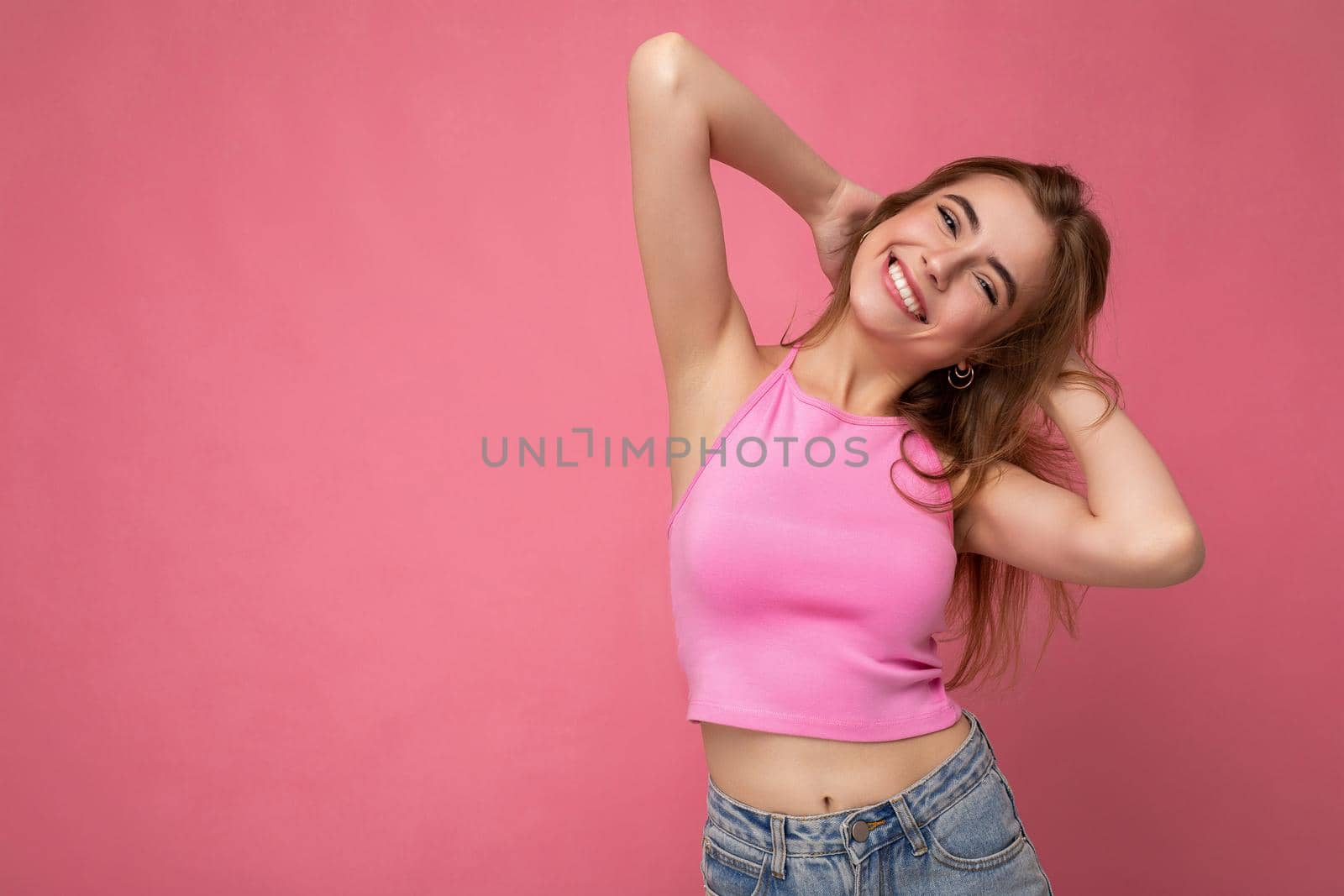 Photo of beautiful positive smiling adult woman wearing stylish clothes standing isolated on colorful background with copy space looking at camera.