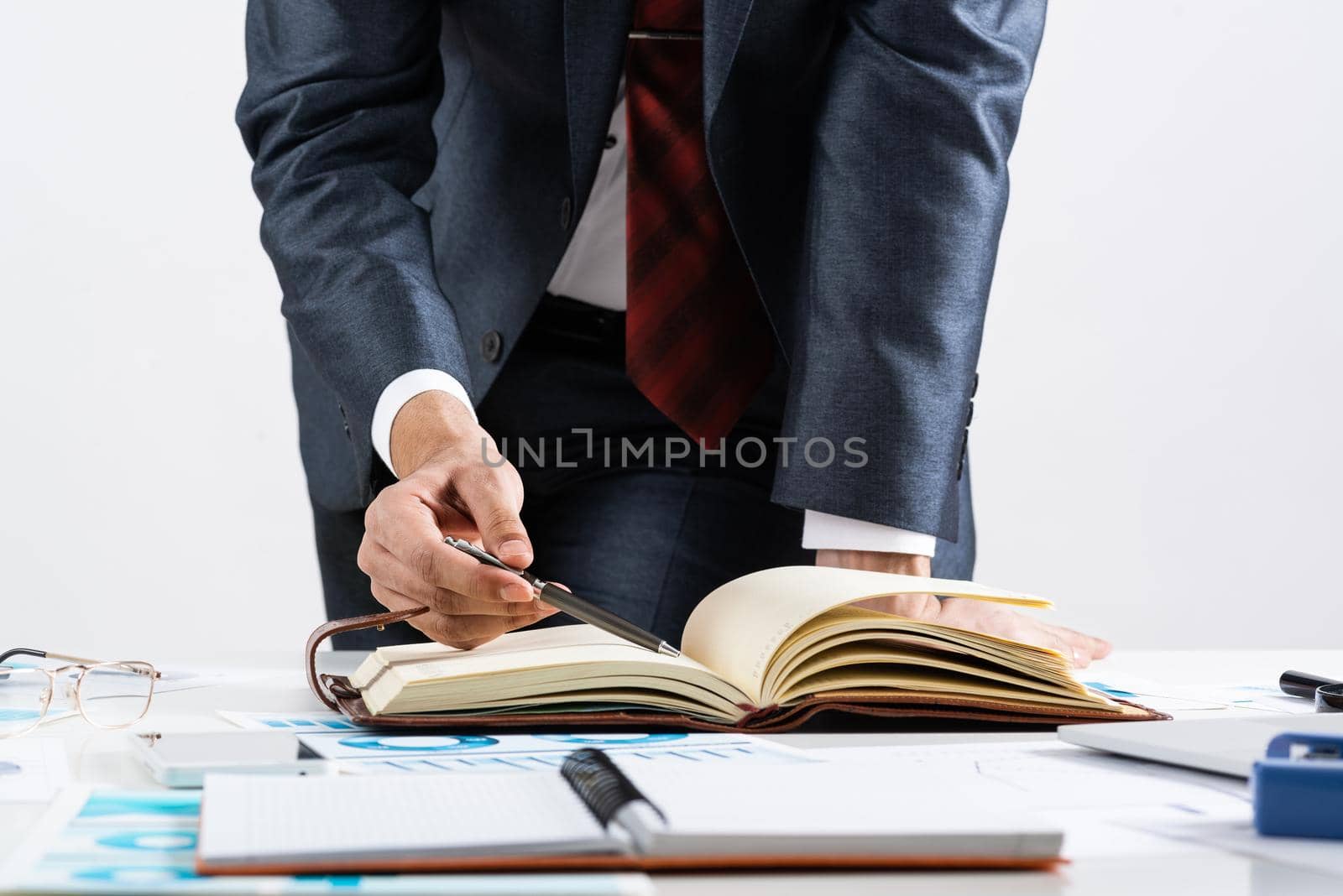 Businessman analyzing financial documents at office desk. Financial expertise and consulting. Manager in suit and tie planning day with personal organizer. Time management and work organization.