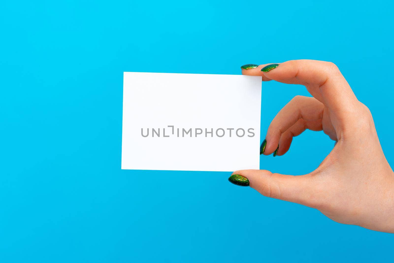 Woman hand holding blank card on blue background, close up.