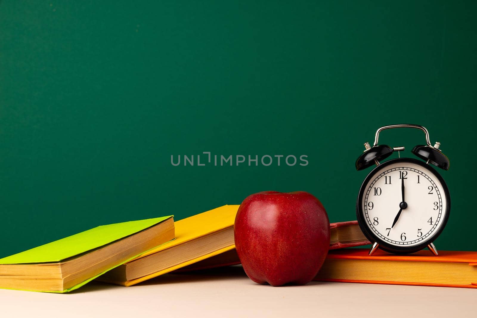 Pile of books and red apple on desk. Back to school concept
