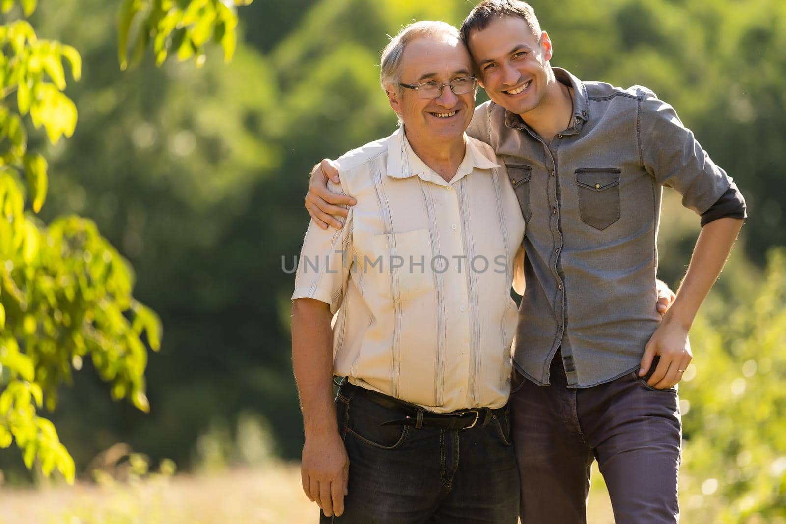 Father and his son looking at the camera in the garden by Andelov13