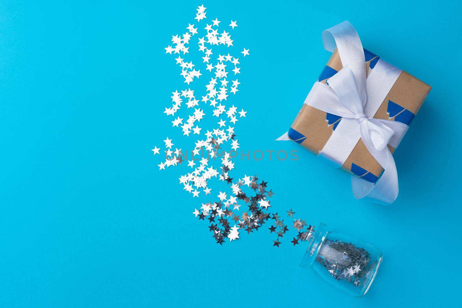 Wrapped Christmas gifts with confetti on blue background top view