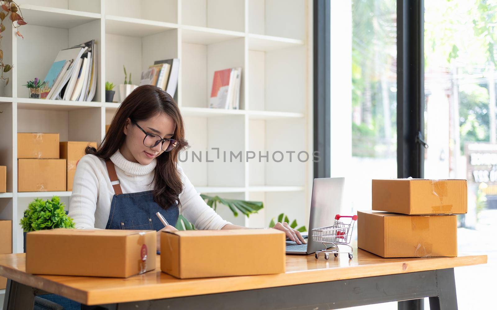 Starting Small business entrepreneur SME freelance,Portrait young woman working at home office, BOX,smartphone,laptop, online, marketing, packaging, delivery, SME, e-commerce concept