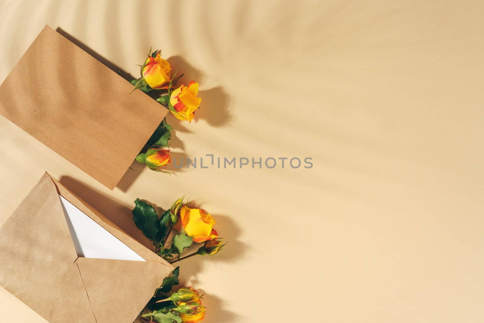 Craft paper envelope with yellow roses on beige background. High quality photo