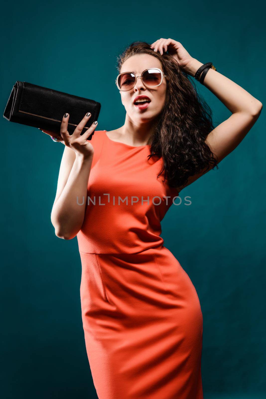 Beautiful girl with a sunglasses and clutch bag in her hands