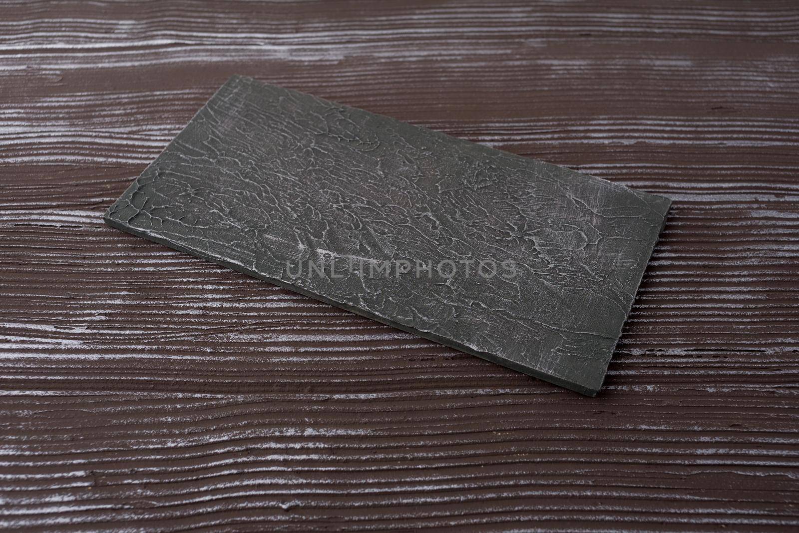 Rectangular piece of slate stone on a woden background - image