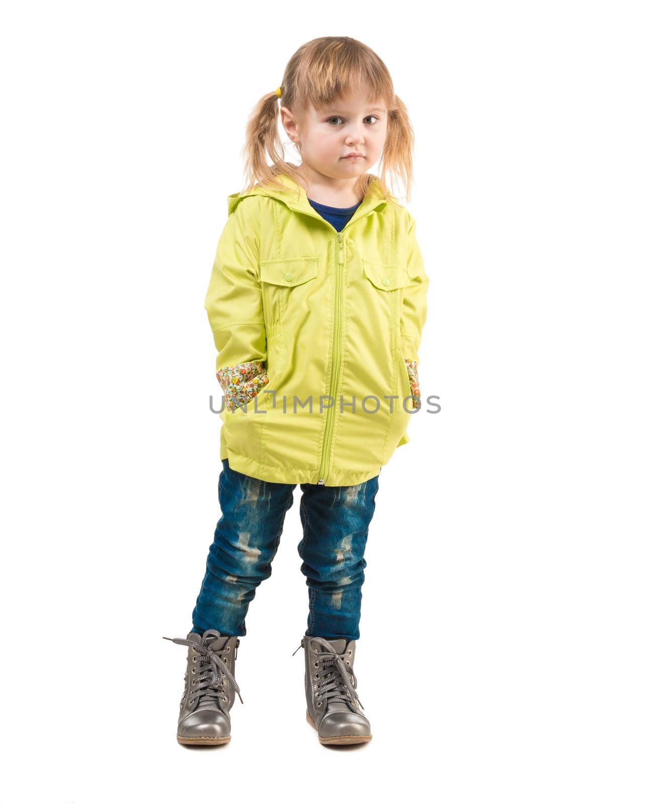 cute little girl in yellow coat and hands in pockets isolated on white background