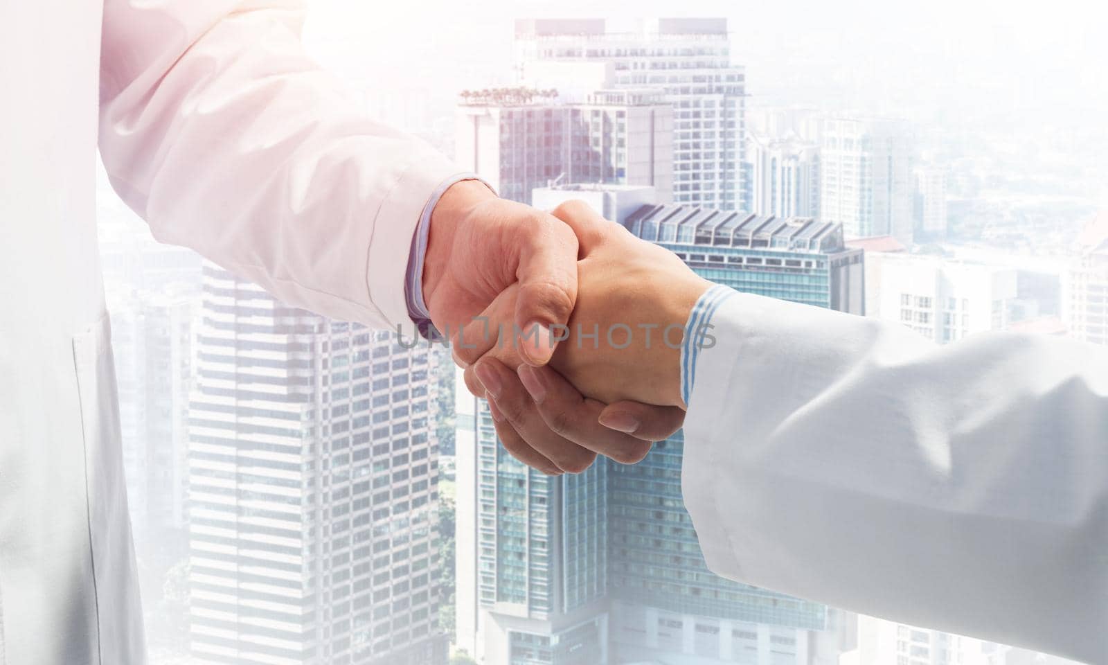 Close-up of the handshake between the two medics. Against the backdrop of the cityscape