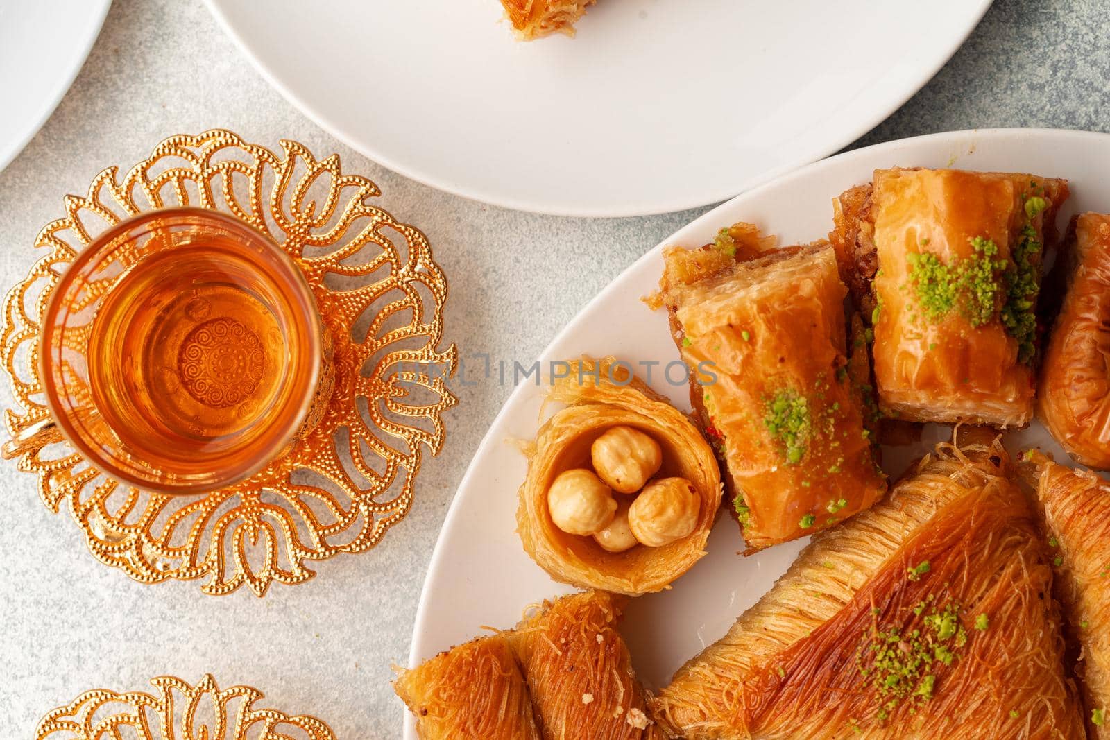 Various Turkish sweets and cup of tea on white textured background, close up