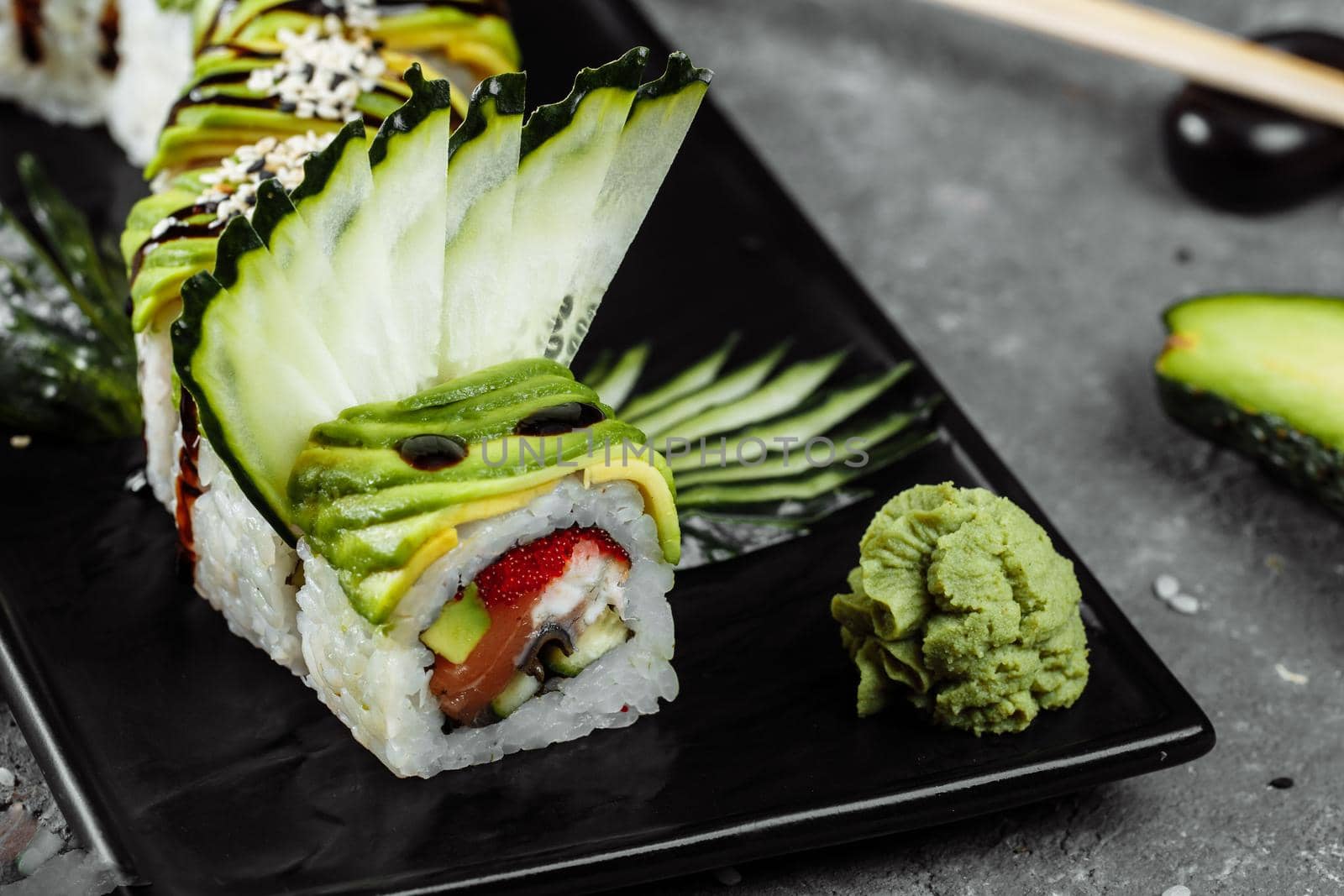 Green dragon sushi roll with eel, avocado, cucumber and ginger, accompanied with fried tempura shrimp. Traditional asian rice sushi healthy seafood.