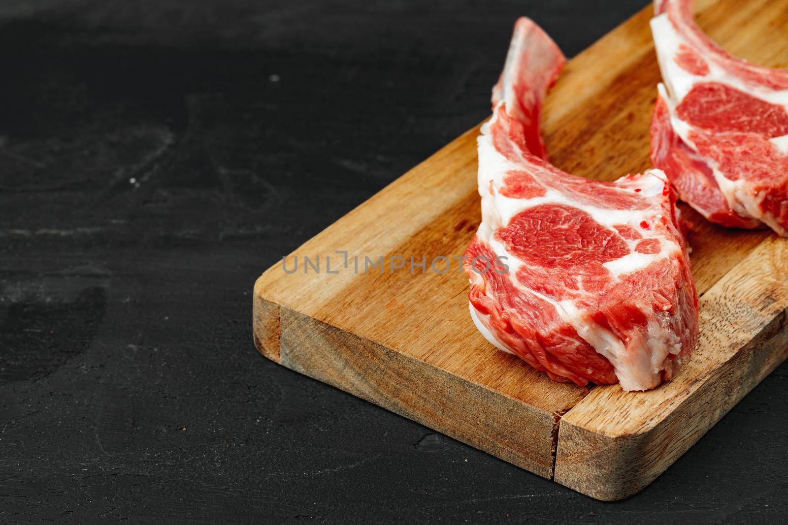 Racks of lamb ready for cooking on dark background, close up