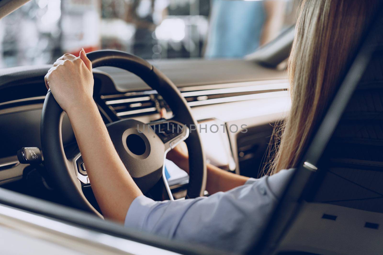 Young woman checking out a new car she is going to buy in car salon