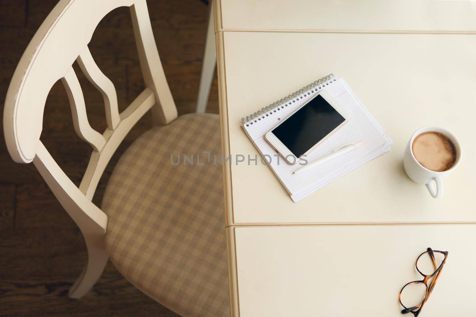 stylish interior in warm pastel colors, an easy chair near the table and white coffee mug with glasses. a place for home office or a place to relax. Retro style interior - cozy working place at home