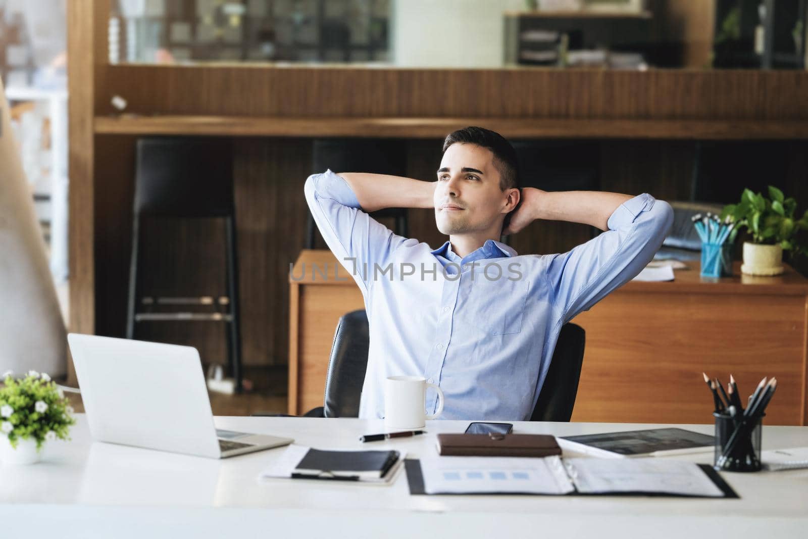 Male marketing manager resting and smiling while working to reduce drowsiness before using computers, iPads and marketing materials. by Manastrong